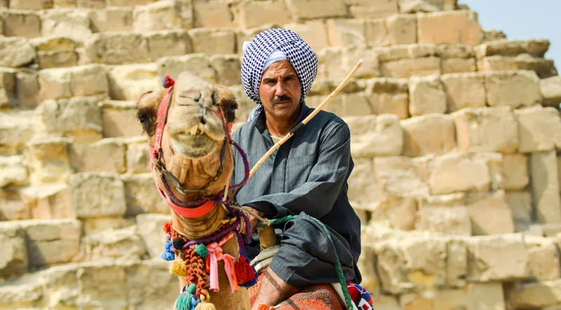 A local Bedouin camel guide in front of a pyramid at Giza
